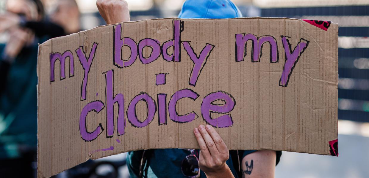 Διαδηλώτρια με χαρτόνι που γράφει το σύνθημα «My body my choice»