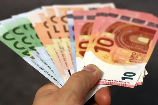 Χέρι που δίνει χαρτονομίσματα ευρώ