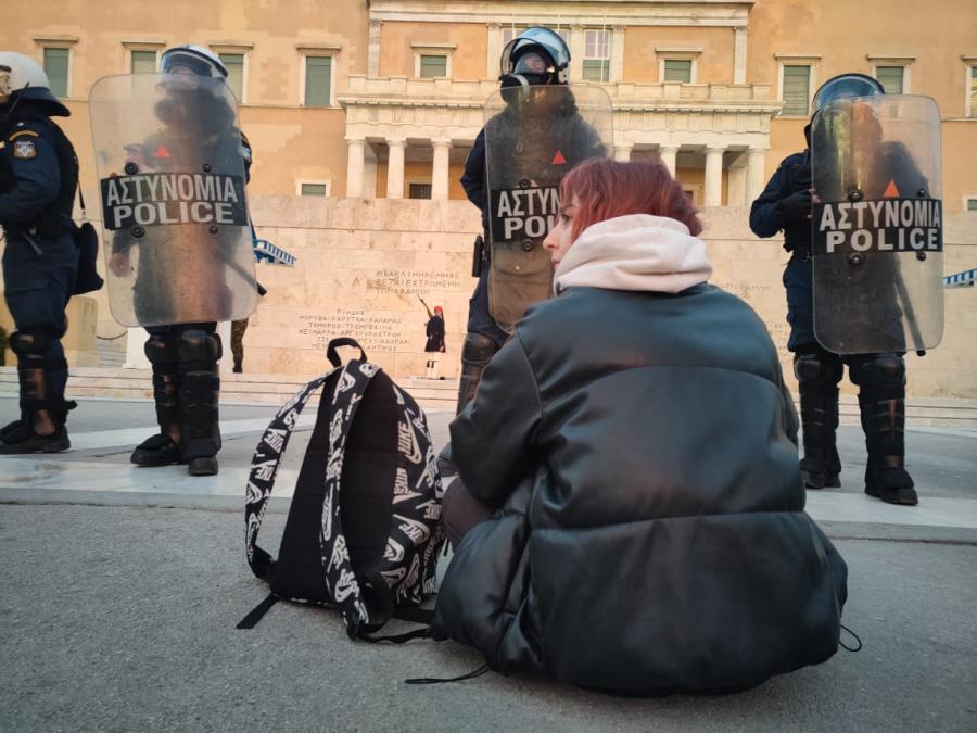 Κοπέλα γυρισμένη πλάτη μπροστά σε άντρες των ΜΑΤ