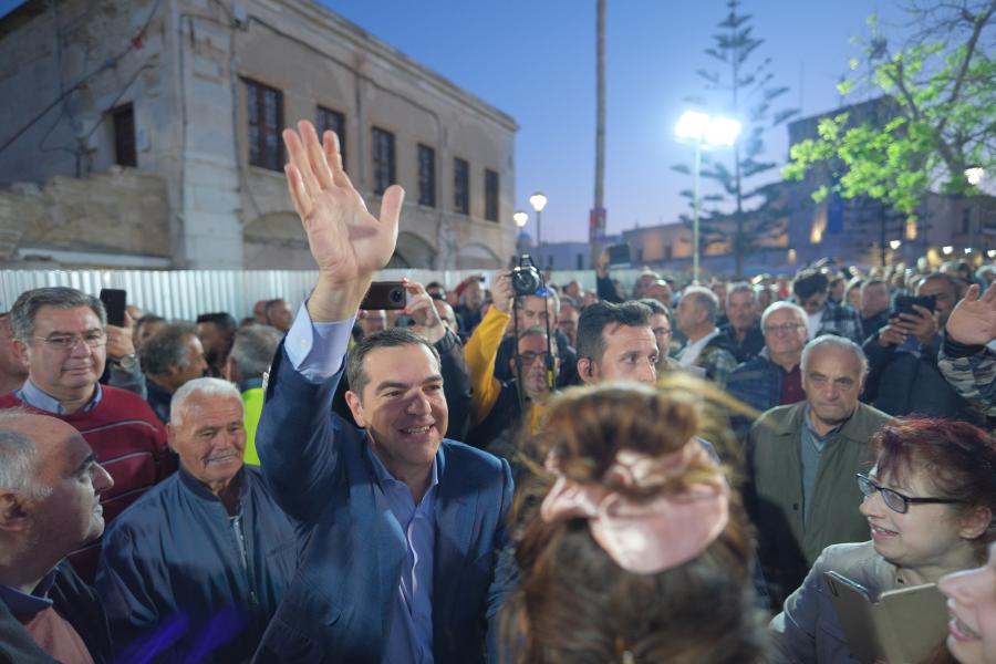 Ο Τσίπρας με το χέρι ψηλά χαιρετά περιτριγυρισμένος από κόσμο 