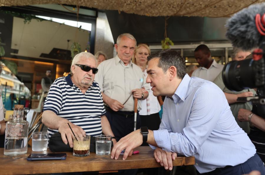 Ο Τσίπρας μιλά σε κύριο καθισμένο σε μαγαζί σε Ζωγράφου-Ιλίσια