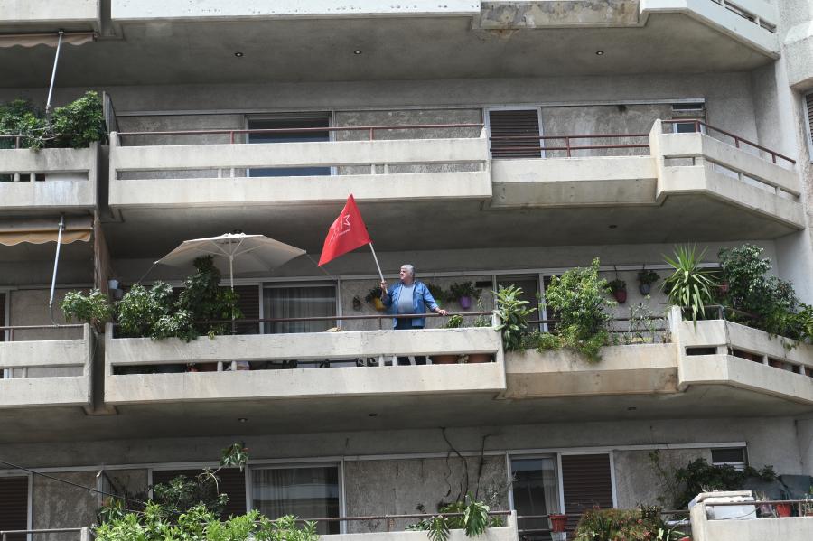 Κύριος στο μπαλκόνι με σημαία του ΣΥΡΙΖΑ