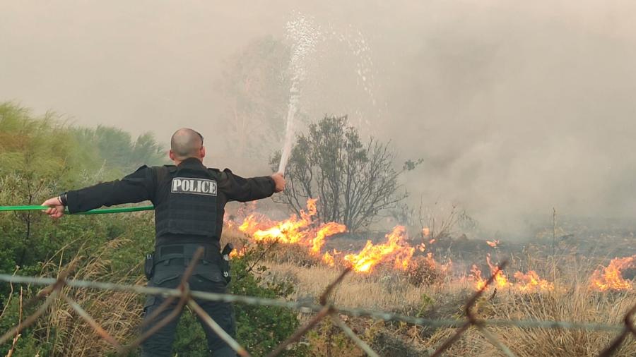 αστυνομικός σβήνει φωτιά με λάστιχο