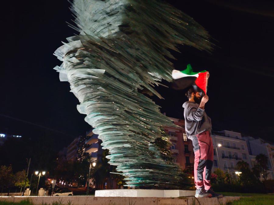 Άντρας στο άγαλμα «Δρομέας» με σημαία της Παλαιστίνης