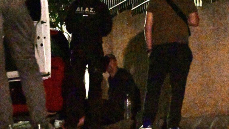 Άνδρας καθισμένος στο πάτωμα με αστυνομικούς μπροστά του