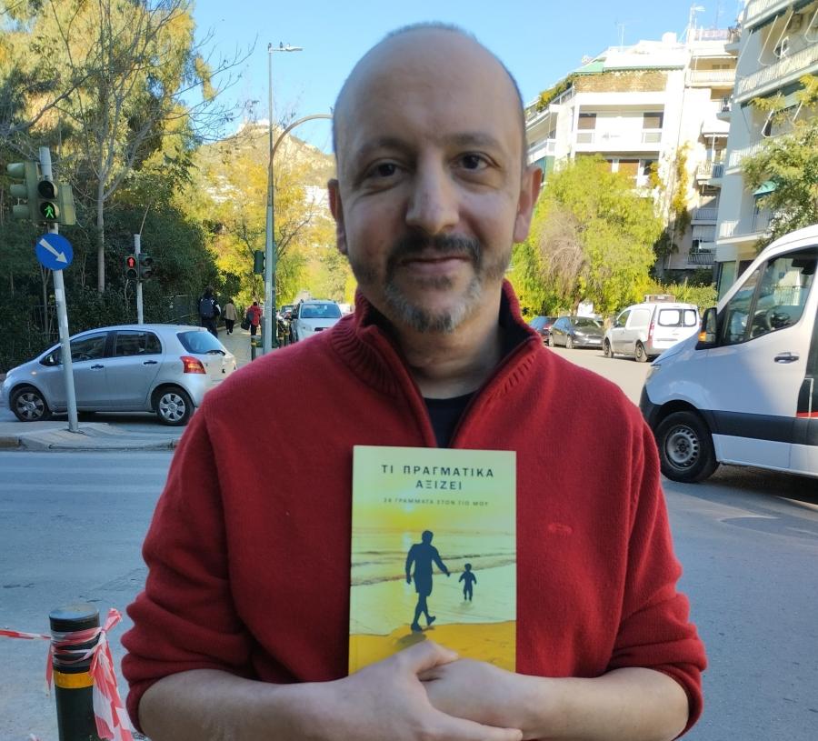 Ο Γιάννης Μπρούζος κρατώντας το βιβλίο του
