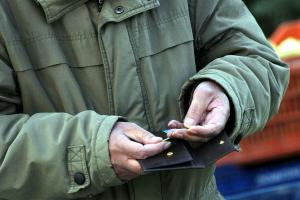 Άνδρας κρατάει πορτοφόλι και μετράει τα κέρματα.