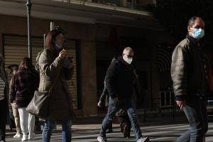 Άνθρωποι διασχίζουν το δρόμο φορώντας μάσκα