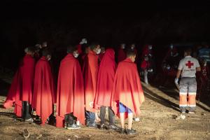 Μετανάστες σκεπασμένοι με κόκκινες κουβέρτες του Ερυθρού Σταυρού