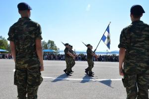 Στρατιώτες στέκονται προσοχή μπροστά από παρέλαση με ελληνική σημαία