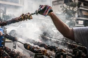 Χέρι που κρατάει την σούβλα πάνω από την ψησταριά την Τσικνοπέμπτη