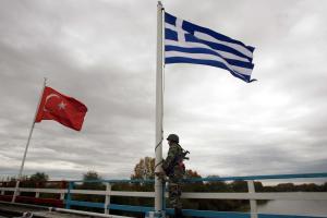 Στρατιώτης στα σύνορα με όπλο και σημαίες της Τουρκίας και της Ελλάδας