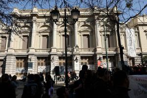 Κόσμος έξω από το κτίριο του Εθνικού Θεάτρου στην πρόσοψη του οποίου υπάρχουν πανό