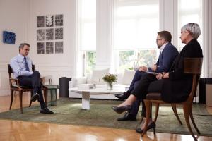Ο Μητσοτάκης καθισμένος σε καρέκλα απέναντι από τους δημοσιογράφους