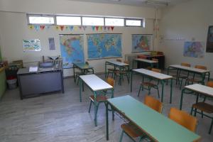 Άδεια σχολική αίθουσα με θρανία, την έδρα και χάρτες στους τοίχους