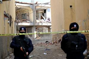 Τούρκοι αστυνομικοί με στολές και όπλα μπροστά από ερείπια και πίσω από κορδέλα