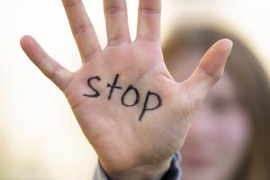 ανοιχτή παλάμη κοπέλας που γράφει την λέξη «Stop»