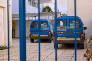Αυτοκίνητα των ΕΛΤΑ σε πάρκινγκ πίσω από σίδερα πόρτας