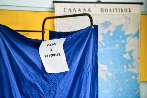 Παραβάν σε εκλογικό κέμντρο με χαρτί πάνω του που γράφει «μέχρι δύο σταυρούς»