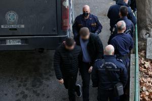 Αστυνομικός πίσω από ανθρώπους δίπλα σε όχημα της ΕΛΑΣ
