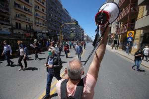 Άντρας με ντουντούκα στραμμένος προς κόσμο που κατεβαίνει τον δρόμο