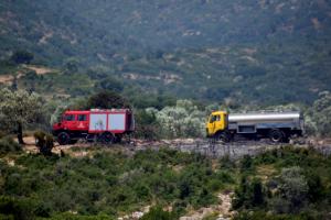 πυροσβεστικό και πίσω υδροφόρα κινούνται σε δρόμο μέσα σε χαμηλή βλάστηση