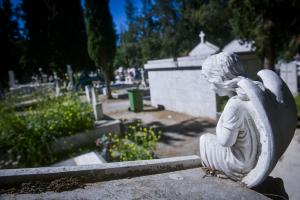 Μαρμάρινο άγαλμα αγγέλου σε νεκροταφείο και πίσω τα μνήματα