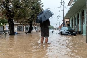 Πολίτης περπατά σε πλημμυρισμένο δρόμο στο Βόλο,