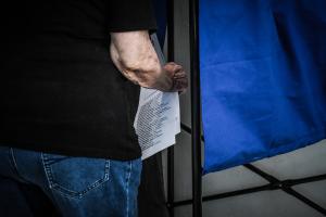 Άνδρας με ψηφοδέλτιο έξω από το παραβάν