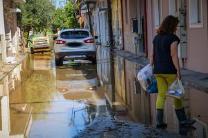 Γυναίκα με σακούλες στο χέρι σε πλημμυρισμένο δρόμο