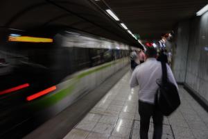 Άντρας με τσάντα στην πλάτη περπατά σε σταθμό του Μετρό την ώρα που φτάνει το τρενο