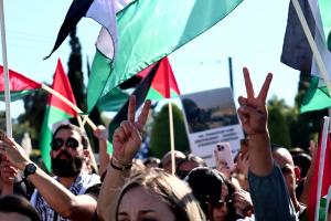 Κόσμος με σημαίες της Παλαιστίνης και κάνοντας το σήμα της νίκης διαδηλώνει για την σφαγή στη Γάζα
