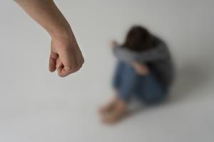 Γροθιά και πίσω κοριτσάκι καθισμένο κάτω με τα χέρια να κρύβουν το πρόσωπό του