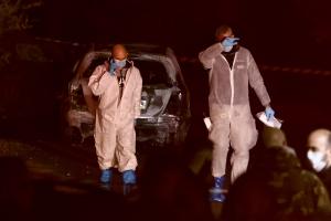 Αστυνομικοί ερευνούν το καμένο αυτοκίνητο στη Μάνδρα