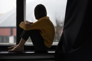 Παιδάκι καθισμένο σε περβάζι παραθύρου κοιτά έξω
