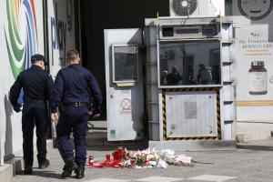 Αστυνομικοί περπατούν δίπλα στο φυλάκιο του ΑΤ Αγίων Αναργύρων με λουλούδια να είναι αφημένα μπροστά του για την 28χρονη Κυριακή που δολοφονήθηκε στο σημείο