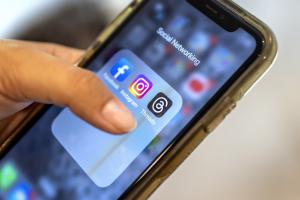 Χέρι κρατά κινητό με τις εφαρμογές Facebbok, Instagram και Threads να φαίνονται στην οθόνη