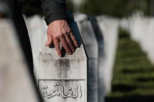 Ένας άνδρας τοποθετεί το χέρι του σε μια ταφόπλακα κατά τη διάρκεια τελετής για την σφαγή στη Σρεμπρένιτσα