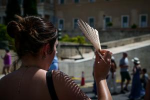 Κοπέλα κάνει σκιά στο πρόσωπό της με βεντάλια στο κέντρο της Αθήνας