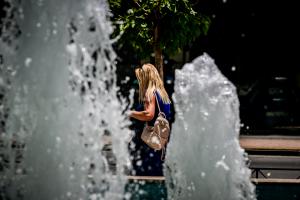 Γυναίκα περνά μπροστά από σιντριβάνι