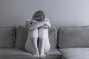 Γυναίκα καθισμένη σε καναπέ κρύβει το πρόσωπό της