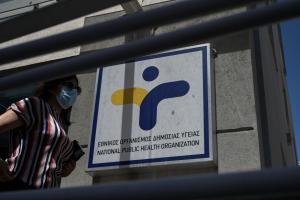 Γυναίκα με μάσκα περπατάει έξω από τον ΕΟΔΥ