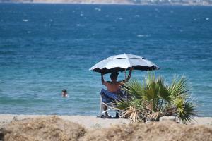 άντρας κάθεται κάτω από ομπρέλα στη θάλασσα