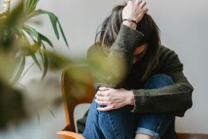 Γυναίκα με λυγισμένα γόνατα που κρύβει το προσωπό της