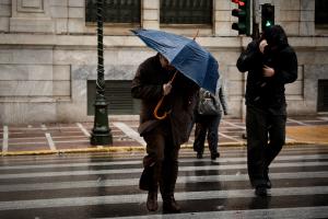 Άνθρωποι περπατούν εν μέσω ισχυρών ανέμων στην Αθήνα
