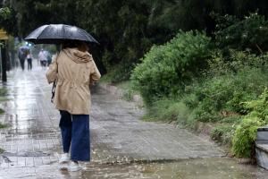 Γυναίκα με ομπρέλα περπατά στη βροχή