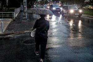 Άντρας με ομπρέλα περπατά στο δρόμο εν μέσω βροχής