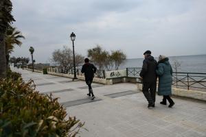 Άνθρωποι με μπουφάν σε παραλιακό πεζόδρόμο
