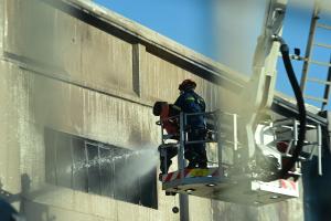 Πυροσβέστες επιχειρούν κατάσβεση πυρκαγιάς με γερανοφόρο όχημα σε εργοστάσιο