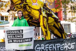Μέλος της Greenpeace με πανό κατά των ορυκτών καυσίμων μπροστά από μπουλντόζα της Shell